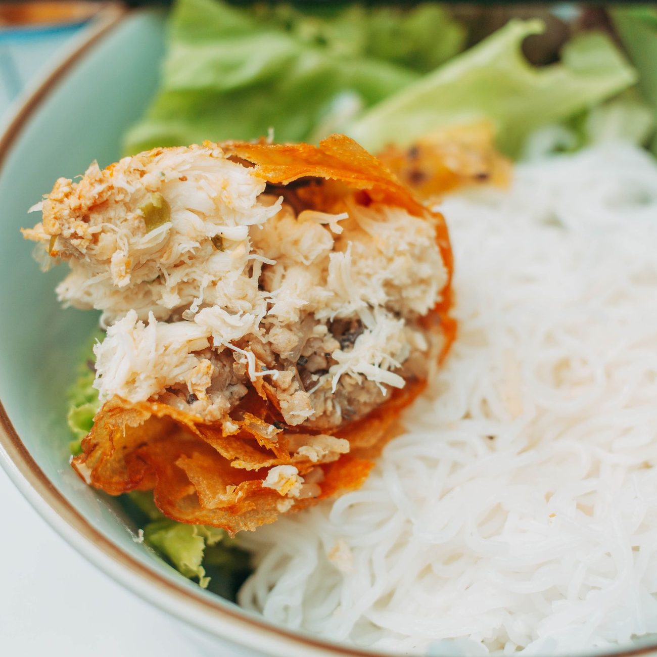 Crispy spring roll served over a bowl of vermicelli noodles